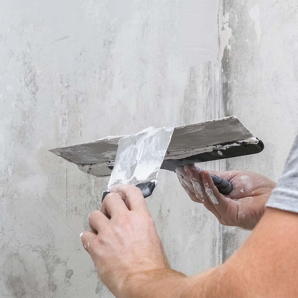 Mican team member using steel trowel to plaster a new build property wall.